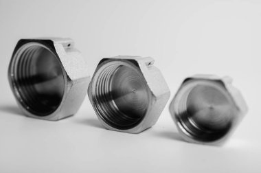 siyah ve beyaz fotoğraf, pirinç metal prizler, eklemler, adaptörler, ışık arka planda izole su için altıgen tuş tıkaçları sıhhi tesisat bağlantılarını ve parçaları kapatın