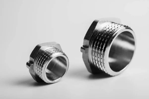 stock image black and white photo, brass metal plugs, joints, adapters, hex key plugs for water isolated on light background close up plumbing connections and parts