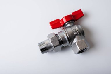 Pirinç rengi metal musluk, kırmızı kapakçık, farklı açı, arka planda izole, yakın plan, tesisat bağlantısı.