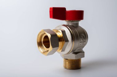 Pirinç rengi metal musluk, kırmızı kapakçık, farklı açı, arka planda izole, yakın plan, tesisat bağlantısı.