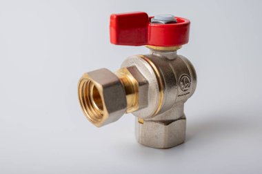 Pirinç rengi metal musluk, kırmızı kapakçık, farklı açı, arka planda izole, yakın plan, tesisat bağlantısı.