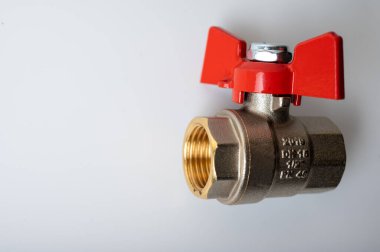 Pirinç rengi metal musluk, kırmızı kapakçık, farklı açı, arka planda izole, yakın plan, tesisat bağlantısı.