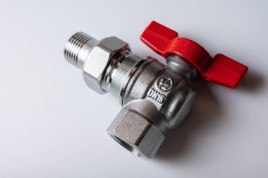 Pirinç rengi metal musluk, kırmızı kapakçık, farklı açı, arka planda izole, yakın plan, tesisat bağlantısı.