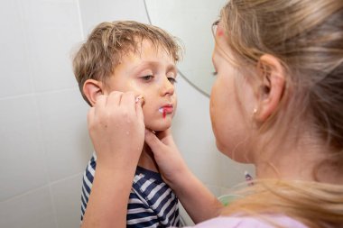 Çocuklar oyun oynuyor, genç erkekler ve genç kızlar birbirlerinin yüzlerini boyuyor ve mutlu bir şekilde gülüyor, Cadılar Bayramı 'na hazırlanıyorlar. Çocuk eğlencesi
