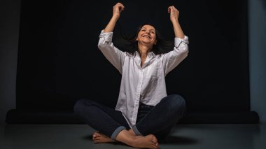 40 yaşlarında genç bir kızın iş portresi, sevimli, duygusal düşünceli, yerde oturuyor, karanlık bir arka plan, kapalı, yansıyan ışık, fotokopi uzayı ile çekiliyor.