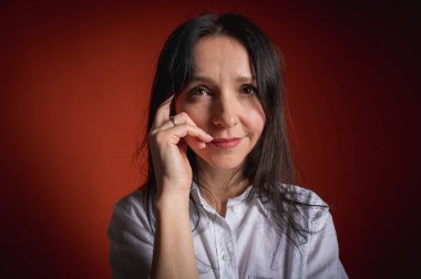 Yakın plan fotoğraf, ciddi, düşünceli, koyu turuncu arka planda bir kızın portresi, kendine güvenli ve dramatik görünüyor. Kadın portresi konsepti. Alçak tuş