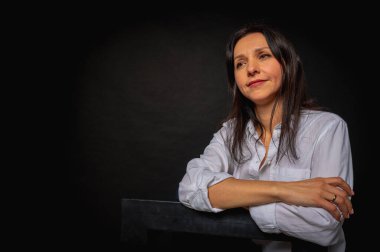 Sevimli ve baştan çıkarıcı esmer kadının uzun bir fotoğrafı. Pantolon giymiş, beyaz gömlekli, siyah arka planda izole bir kadın.