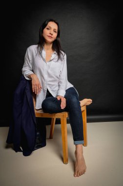 Karanlık bir sandalyede oturan ve ellerini yüzünün yakınında tutan bir kızın duygusal yakın plan portresi. Karanlık bir arka plan, yazmak için yer. El ve vücut hareketleri, portre 