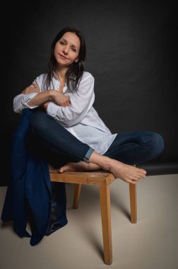 Karanlık bir sandalyede oturan ve ellerini yüzünün yakınında tutan bir kızın duygusal yakın plan portresi. Karanlık bir arka plan, yazmak için yer. El ve vücut hareketleri, portre 