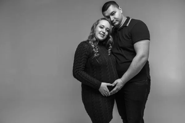 一个快乐的年轻人和他怀孕的妻子站在一起 被隔离在一面白墙上的黑白照片 家庭成长 等待孩子 年轻的家庭 — 图库照片