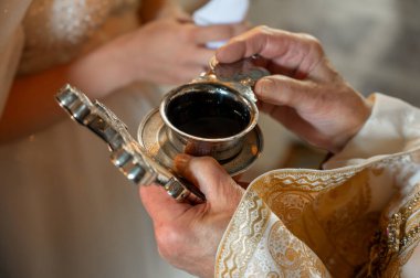 Rahip, gelin ve damadın parmaklarındaki alyansları kutsuyor. Düğün geleneği ve ritüeli. Kilisedeki genç bir çiftin elleri.