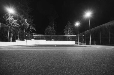 Parktaki spor sahasında yeşil ağaçların arkasında yapay çimen stadyumu var. Güçlü fenerlerle gece aydınlatması, aşağıdan manzara