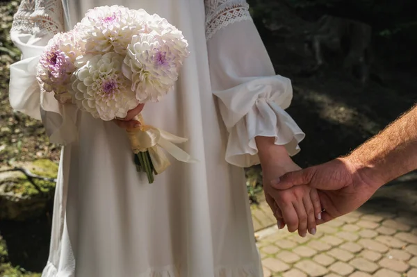Hands and hearts together. A close-up of a loving couple holding hands while walking outdoors in a park