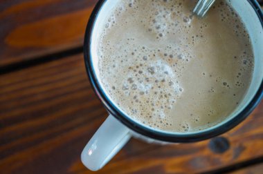 Bir fincan taze kahve ve tahta bir yüzey üzerinde hafif bir kupa, masa. Yukarıdan görüntüle
