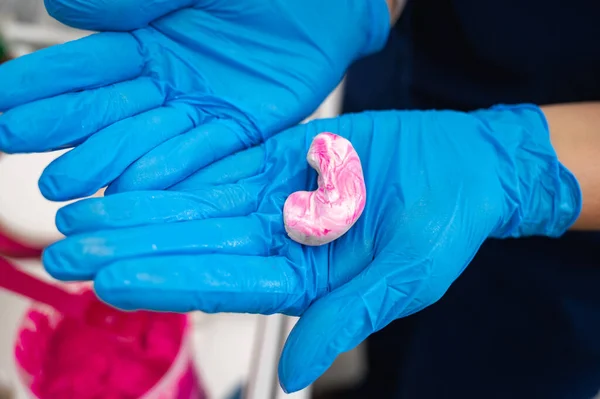 医師は患者の耳管をシリコーン素材で満たし 聴覚クリニックで耳栓を作るために注射器を使用して作られたピンクです 注文するインサートの生産 — ストック写真