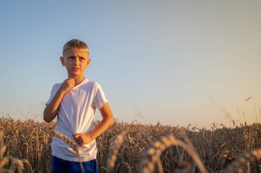 Beyaz tişörtlü küçük bir çocuğun portresi, akşam üstü Ukrayna 'da bir buğday tarlasında, Lviv yakınlarında, yazıtlar için bir yer. Batıda huzurlu bir gökyüzü