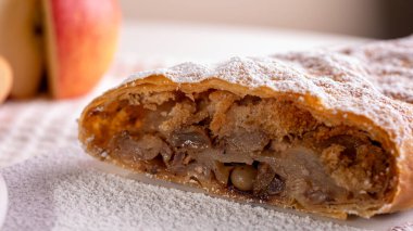 Elma ve tarçınla doldurulmuş lezzetli meyveli turta parçaları hafif bir arka planda hafif bir tabakta. Yazı için yer