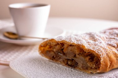 Elma ve tarçınla doldurulmuş bir parça lezzetli turta, kahve telvesi ve hafif arka planlı bir tabakta. Yazmak için yer var. Görüntüyü kapat