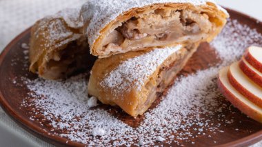 Elma ve tarçınla doldurulmuş lezzetli meyveli turta parçaları hafif bir arka planda hafif bir tabakta. Yazmak için yer var. Manzarayı kapat. Ev yapımı Ukrayna hamur işleri