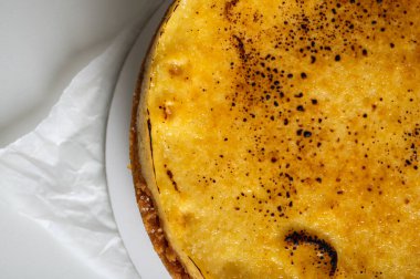 Kabuklu peynirli kek, bir parça kesilmiş, hafif bir tabakta, arka planda. Pasta, hamur işi.