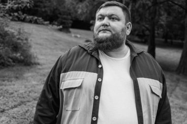 Siyah beyaz portre, şık duygusal iş adamı parkın dışında sakallı adam, kollarını önünde kavuşturdu. Seçici odaklanma. Yazı için yer