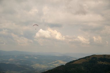 Dağların tepesindeki vadide paraşütçü, Ukrayna dağlarında aktif eğlence.