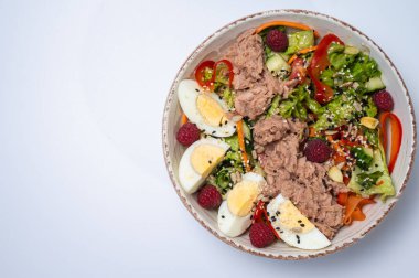 Beyaz arka planda marul ve yumurtalı ton balığı salatası.