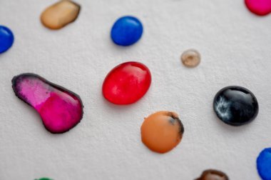 Çok renkli bir su damlası. Arka planda, açık bir çarşaf üzerinde. Görüntüyü kapat