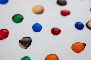 Çok renkli bir su damlası. Arka planda, açık bir çarşaf üzerinde. Görüntüyü kapat