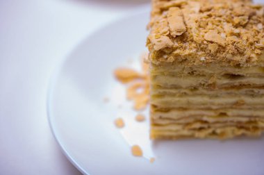 Yakın görüş, açık yüzeyde Napolyon pastası, beyaz tabak, yan görüş. Yazı için yer