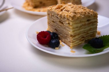 Yakın görüş, açık yüzeyde Napolyon pastası, beyaz tabak, yan görüş. Yazı için yer