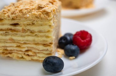 Yakın görüş, açık yüzeyde Napolyon pastası, beyaz tabak, yan görüş. Yazı için yer