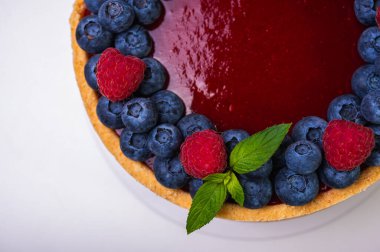 Taze böğürtlen, yabanmersini, ahududu ve nane yapraklarıyla süslenmiş cheesecake 'in yakın çekimi. Şekerlemeler, pişirme, parlak renkler