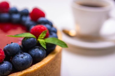 Taze böğürtlen, yabanmersini, ahududu ve nane yapraklarıyla süslenmiş cheesecake 'in yakın çekimi. Şekerlemeler, pişirme, parlak renkler