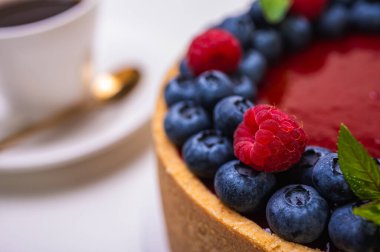 Taze böğürtlen, yabanmersini, ahududu ve nane yapraklarıyla süslenmiş cheesecake 'in yakın çekimi. Şekerlemeler, pişirme, parlak renkler