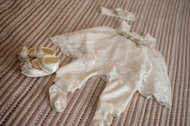 Üniformalı bir zeminde vaftizden önce küçük bir çocuğun giysileri. Çocuk alınıyor.