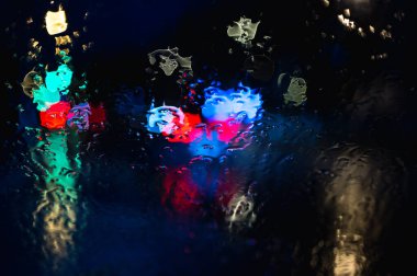 Su ve yağmur damlaları camlara damlıyor, soyut bir manzara. Gece şehri Bokeh