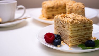 Yakın görüş, açık yüzeyde Napolyon pastası, beyaz tabak, yan görüş. Yazı için yer