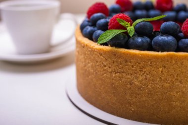 Taze böğürtlen, yabanmersini, ahududu ve nane yapraklarıyla süslenmiş cheesecake 'in yakın çekimi. Şekerlemeler, pişirme, parlak renkler