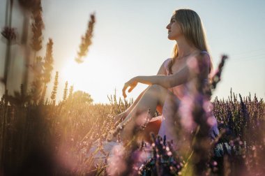Gün batımının ışınlarında, beyaz elbiseli rahat bir genç kızın yan portresi, beyaz bir bankta oturuyor, temiz hava soluyor, güneşli bir günde lavanta tarlasında oturuyor, uzaklara bakıyor, düşünüyor. Yazmak için bir yer