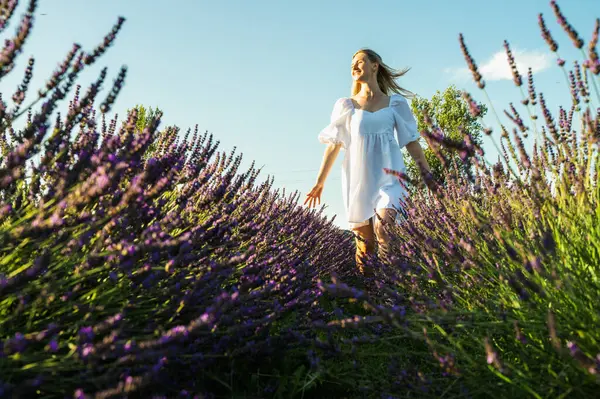 portrait of a relaxed young girl in a white dress, in thought, breathing fresh air, sitting in a lavender field on a sunny day, looking away, thinking
