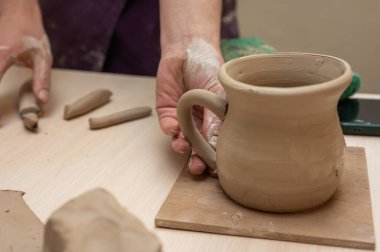 Clay, çömlek ya da el sanatları atölyesinde küçük işletme atölyesinde sanatsal bir bardak ya da kupa kalıbı üzerinde çalışıyor. Heykelde el işi ürünleri üreten yaratıcı sanatçı ya da işçilerin eli