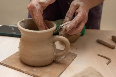 Clay, çömlek ya da el sanatları atölyesinde küçük işletme atölyesinde sanatsal bir bardak ya da kupa kalıbı üzerinde çalışıyor. Heykelde el işi ürünleri üreten yaratıcı sanatçı ya da işçilerin eli