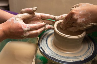 Clay, seramik ya da bir tasarım atölyesinde sanatsal bardak ya da kupa üzerinde çalışan eller. Heykel sanatı yapan yaratıcı bir sanatçı ya da işçinin eli