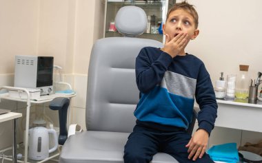 Küçük bir çocuk, sarışın bir genç, muayene için otolaryngolojistin ofisinde oturuyor, korkuyor, elleriyle ve korkuyla kendinden uzaklaştırıyor. Yazmak için yer