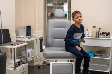 Küçük bir çocuk, sarışın bir genç, otolaryngolojistin ofisinde oturuyor, sınavı bekliyor, endişeli ama gülümsüyor. Yazı için yer