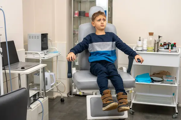 a little boy, a fair-haired teenager, sits in the otolaryngologist\'s office, waiting for an examination, worried, but smiling. Place for inscription