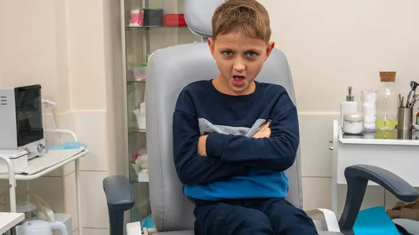 a little boy, a fair-haired teenager, sits in the otolaryngologist\'s office, waiting for an examination, worried, but smiling. Place for inscription