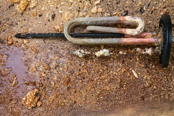 Heating element of an electric water heater with a rusty anode and a tube covered with scale, a damaged part. Maintenance and repair.
