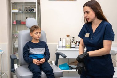 Küçük bir çocuk, sarışın bir genç, otolaringolojistin ofisinde oturuyor, doktorda kulak muayenesi yaptırıyor, endişeli, duygusal, ama gülümsüyor. Fiziksel muayene.